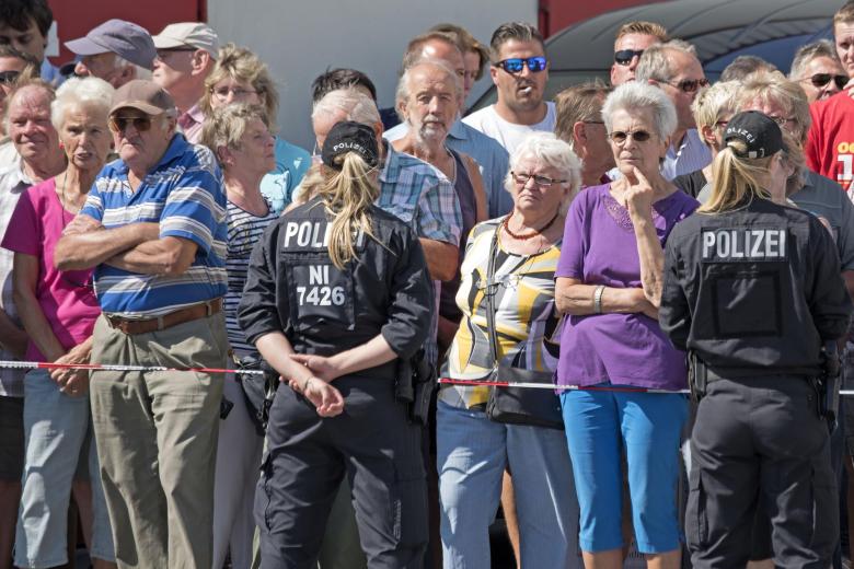 People-stand-behind-police-guards-during