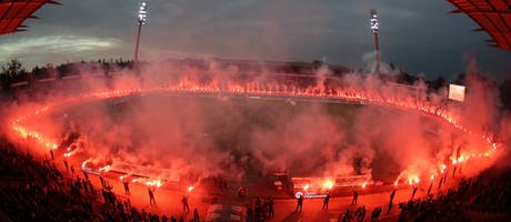 Am-Spielfeldrand-stehen-KSC-Fans-mit-rot