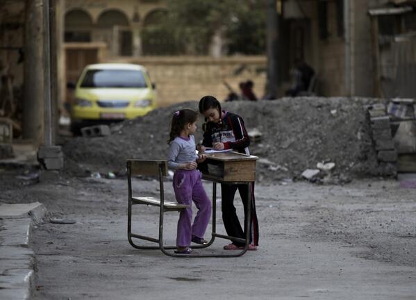 Two girls are using a school desk in the