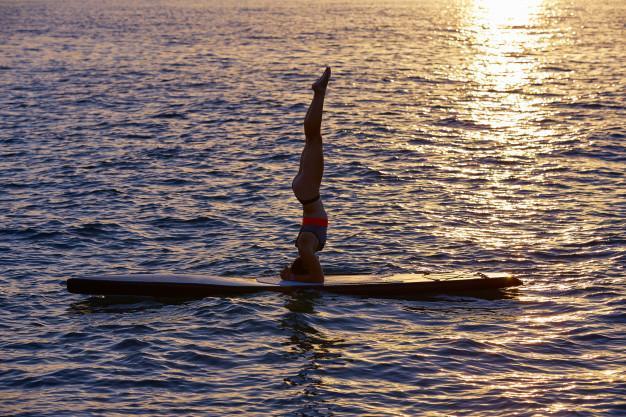 yogamaedchen-ueber-sup-stehen-surfbrett 